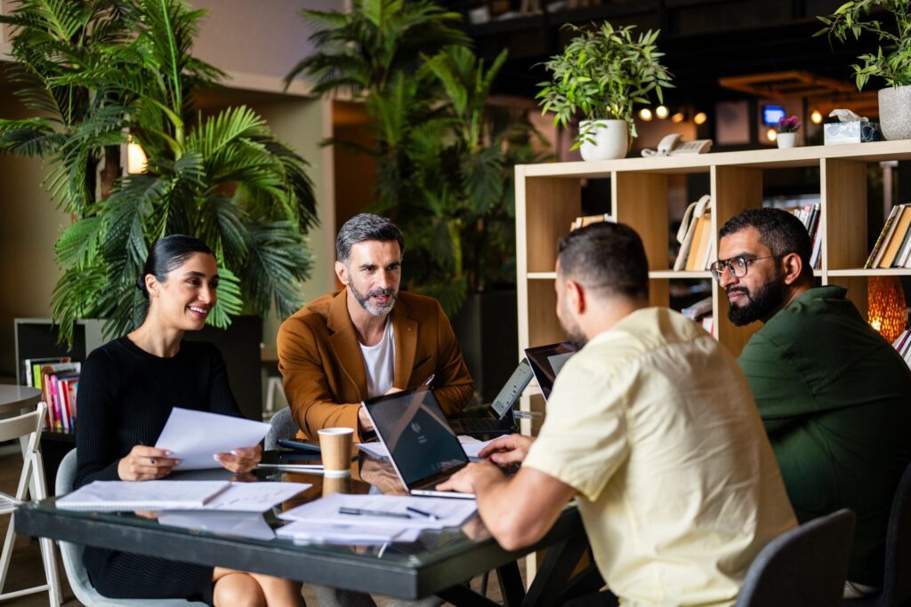 Four multiracial business colleagues in meeting with laptops and paperwork